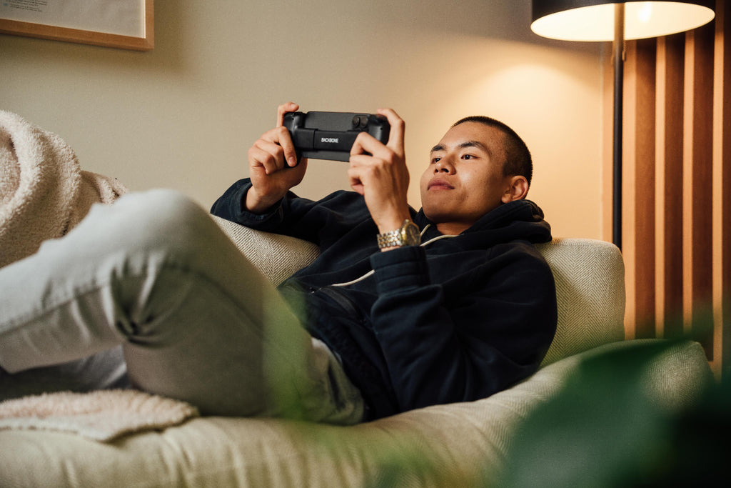 man with backbone in hand laying on o sofa playing games